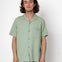 Man wearing a light green short-sleeve shirt against a white background