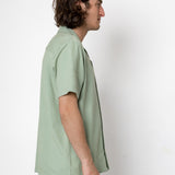 Man wearing a light green shirt against a white background