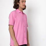 Man wearing a pink shirt against a white background