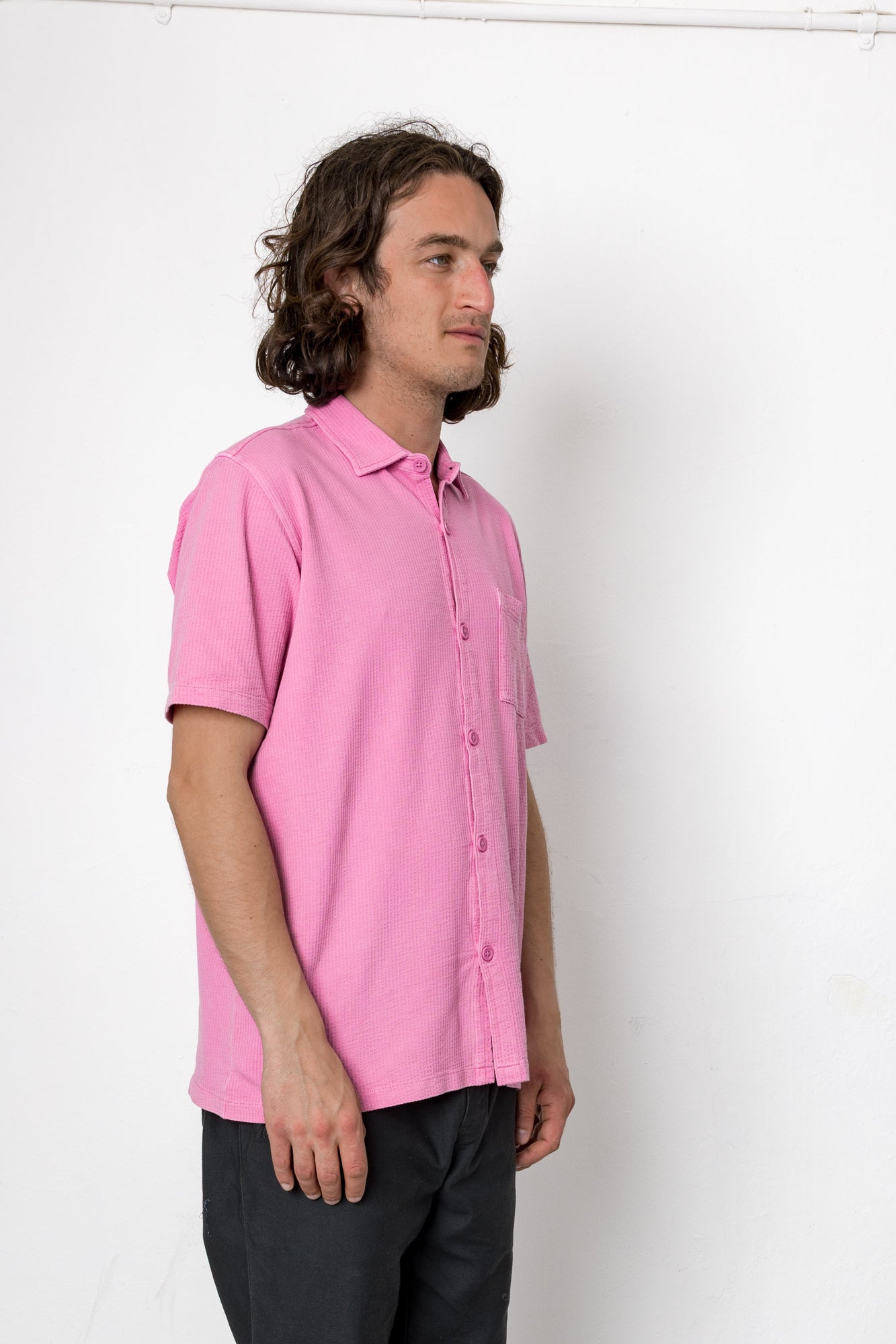 Man wearing a pink shirt against a white background