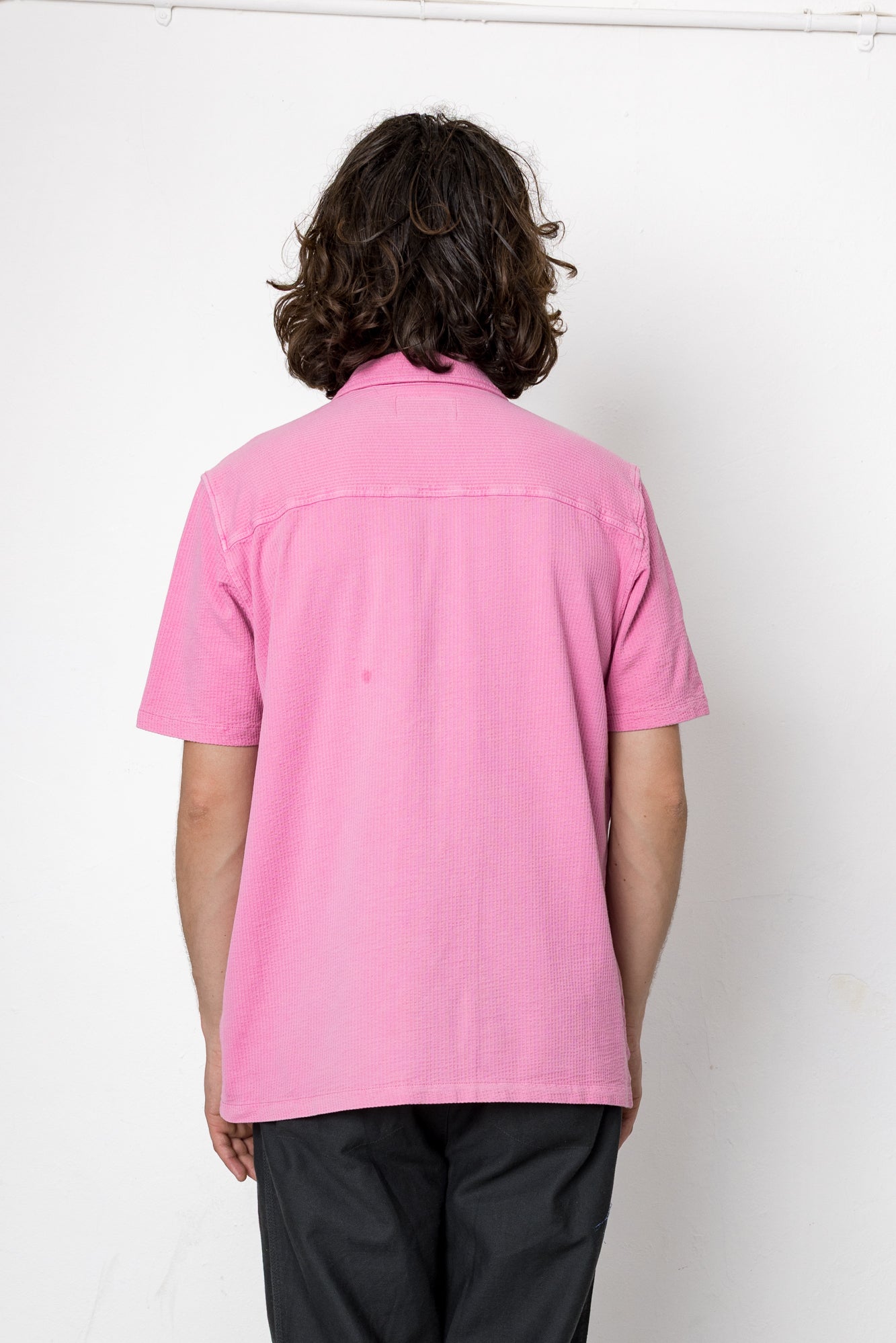 Person wearing a pink shirt from behind on a white background