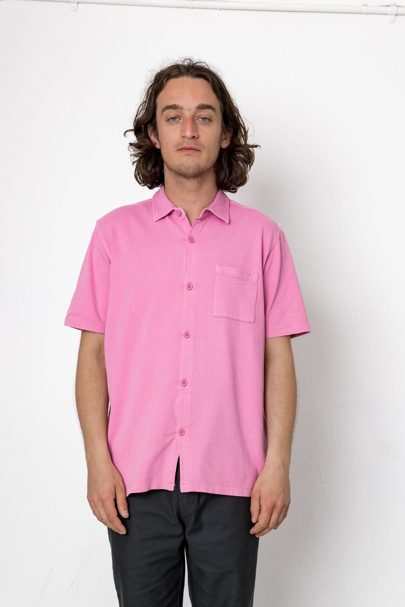Person wearing a pink shirt against a white background