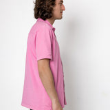 Person wearing a pink polo shirt against a white background