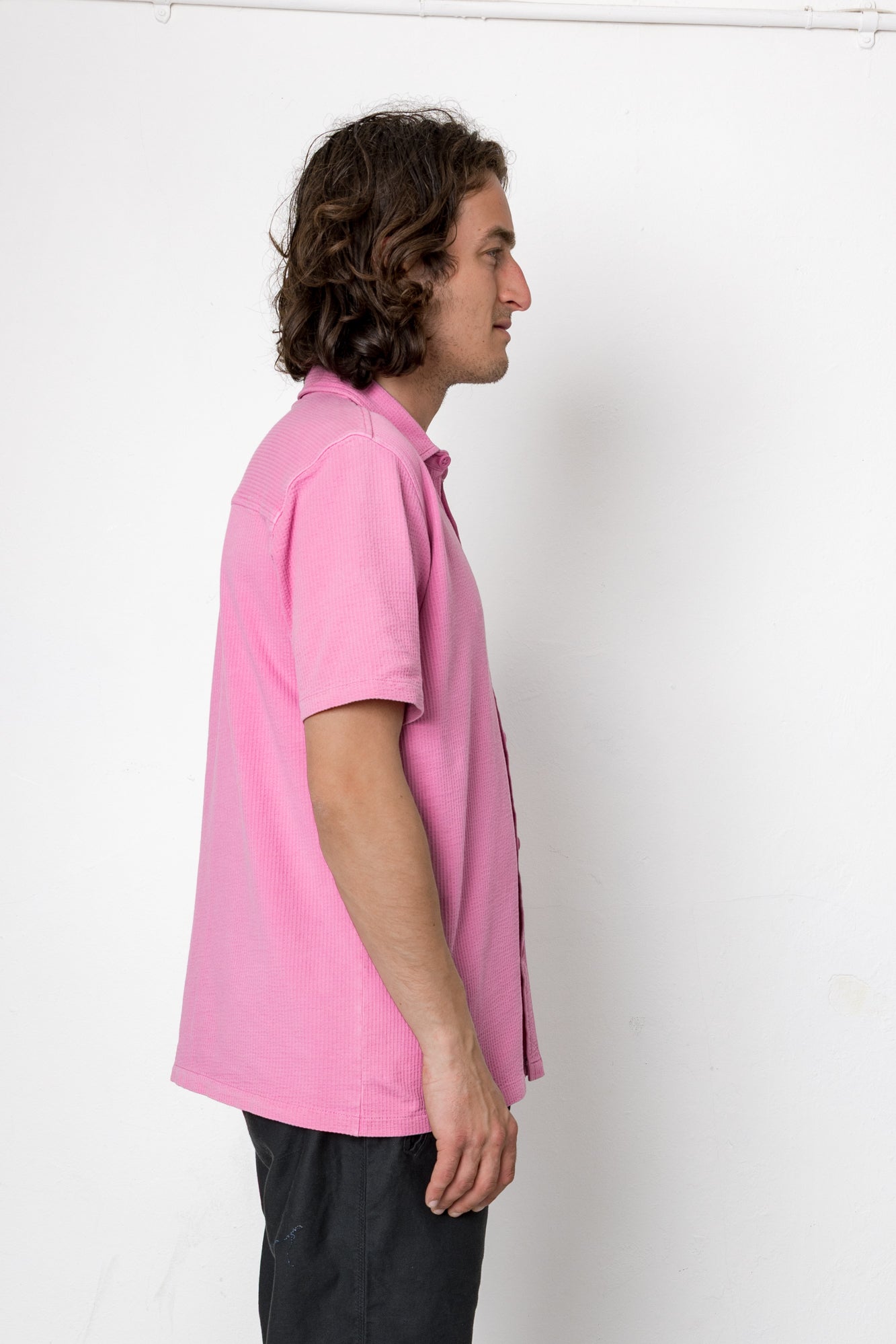 Person wearing a pink polo shirt against a white background
