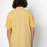 Person wearing a yellow polo shirt against a white background