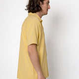 Man wearing a yellow polo shirt against a white background