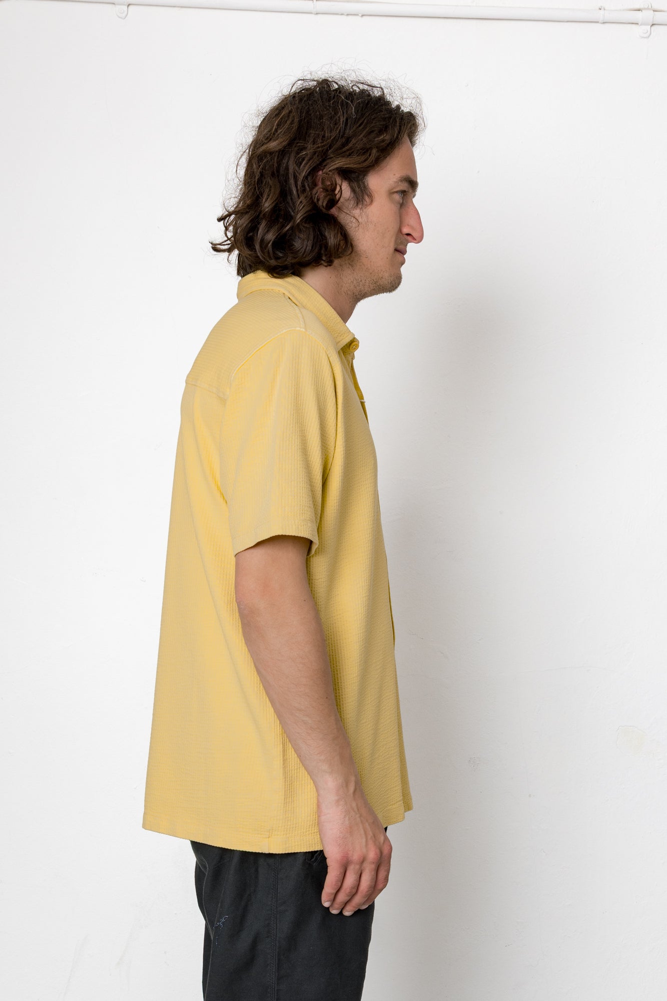 Man wearing a yellow polo shirt against a white background