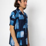 Man wearing a blue patterned shirt against a white background