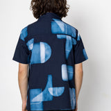 Person wearing a blue patterned shirt with a white background