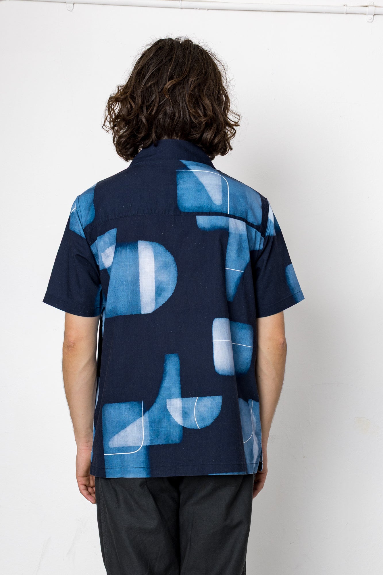 Person wearing a blue patterned shirt with a white background