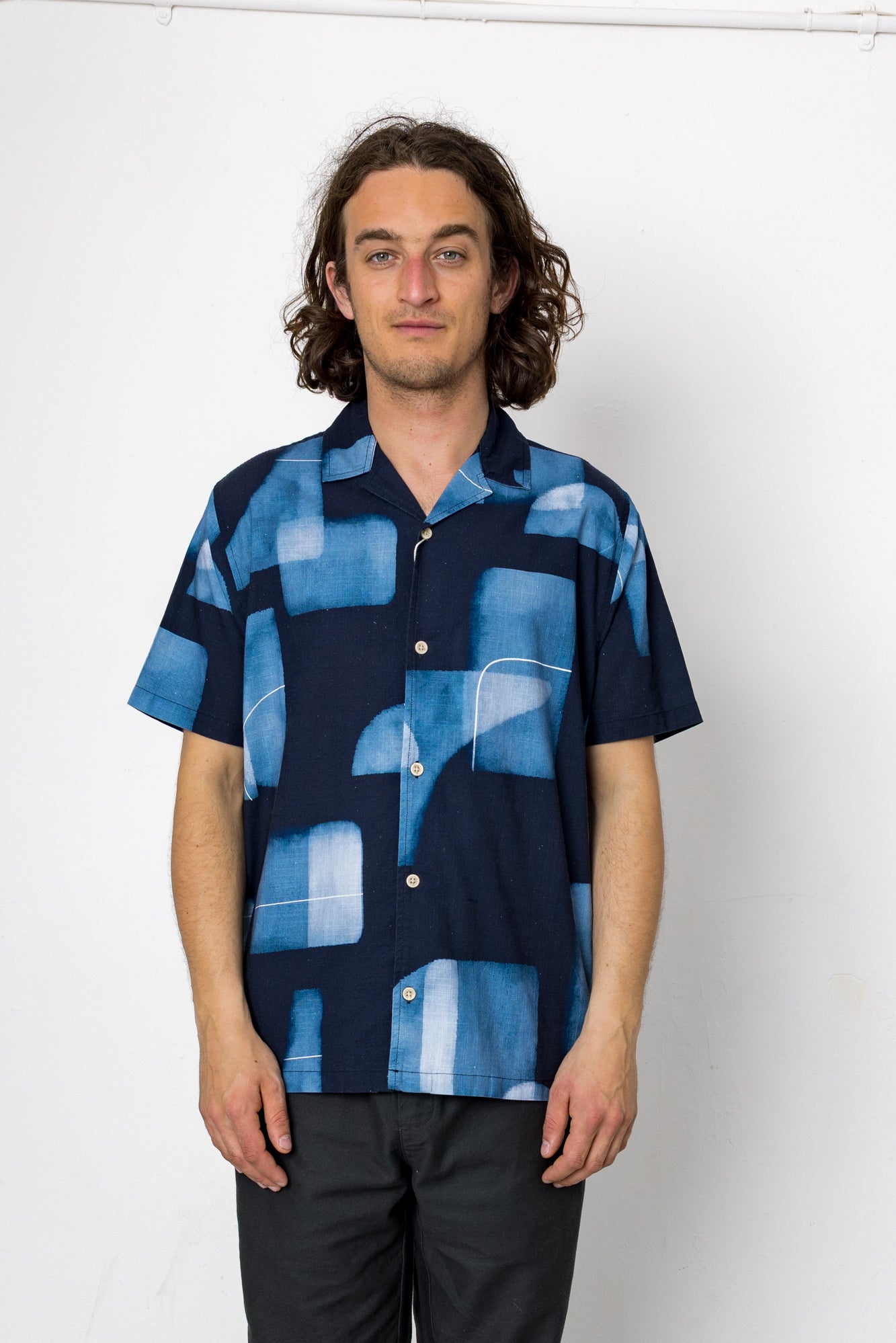 Man wearing a blue patterned shirt against a white background