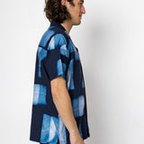 Man wearing a blue patterned shirt against a white background