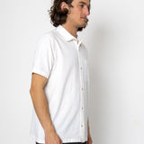 Man wearing a white short-sleeve shirt against a plain background