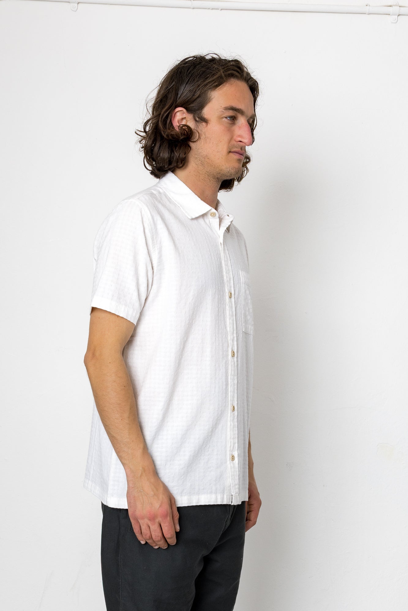 Man wearing a white short-sleeve shirt against a plain background