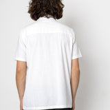 Person wearing a white shirt and black pants against a plain background