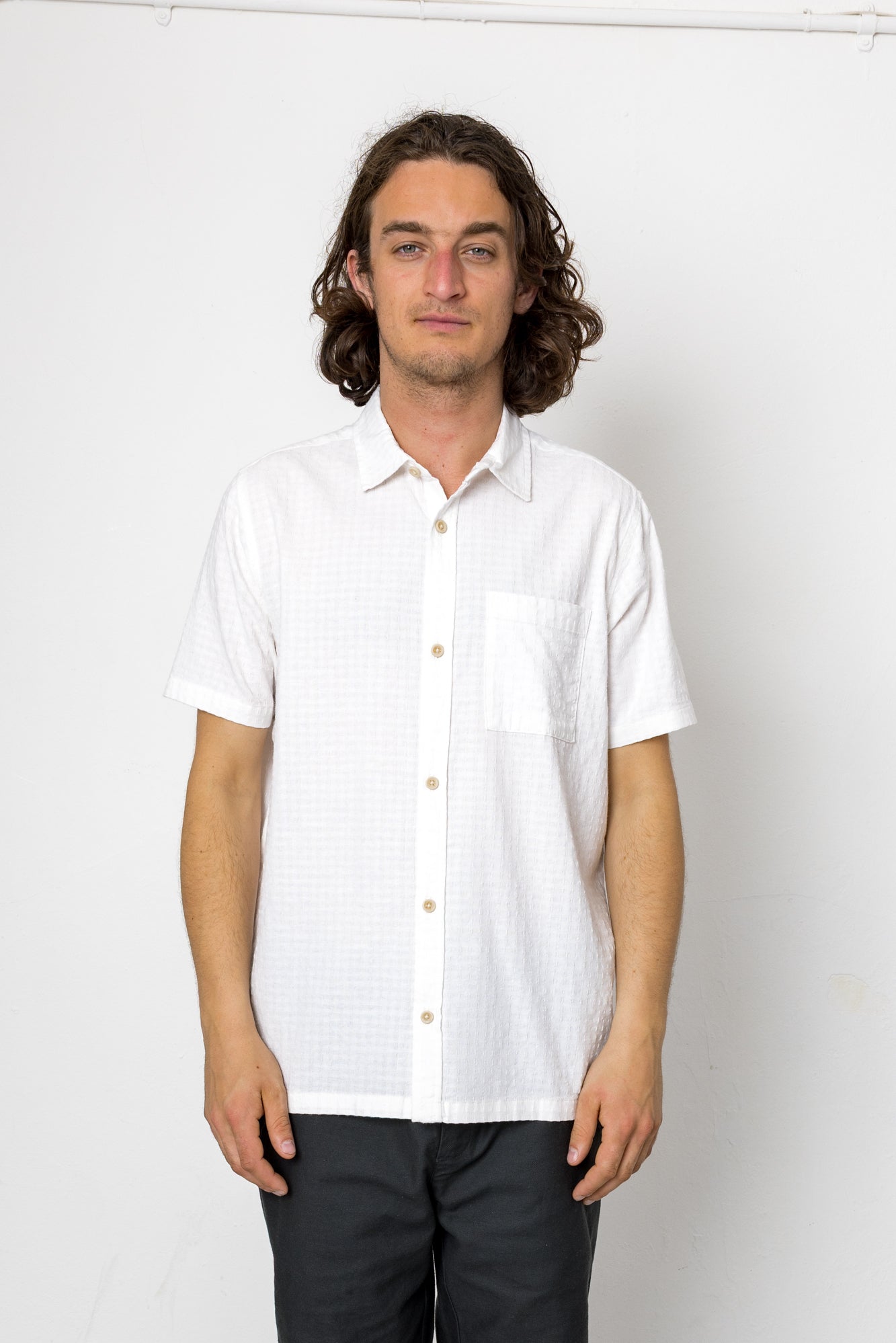 Man wearing a white short-sleeve shirt against a plain background
