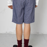 Person wearing blue shorts, white shirt, maroon socks, and black shoes on a plain background