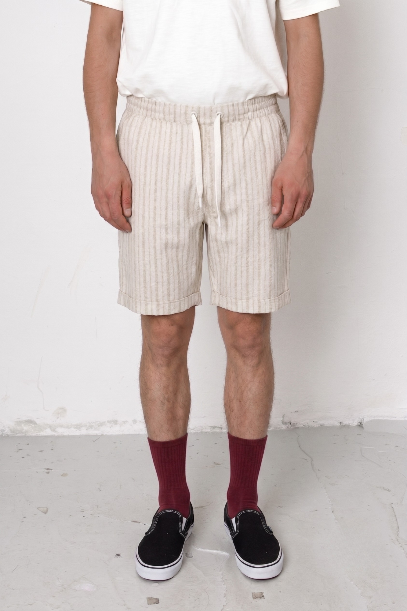 Person wearing beige shorts and maroon socks against a white background