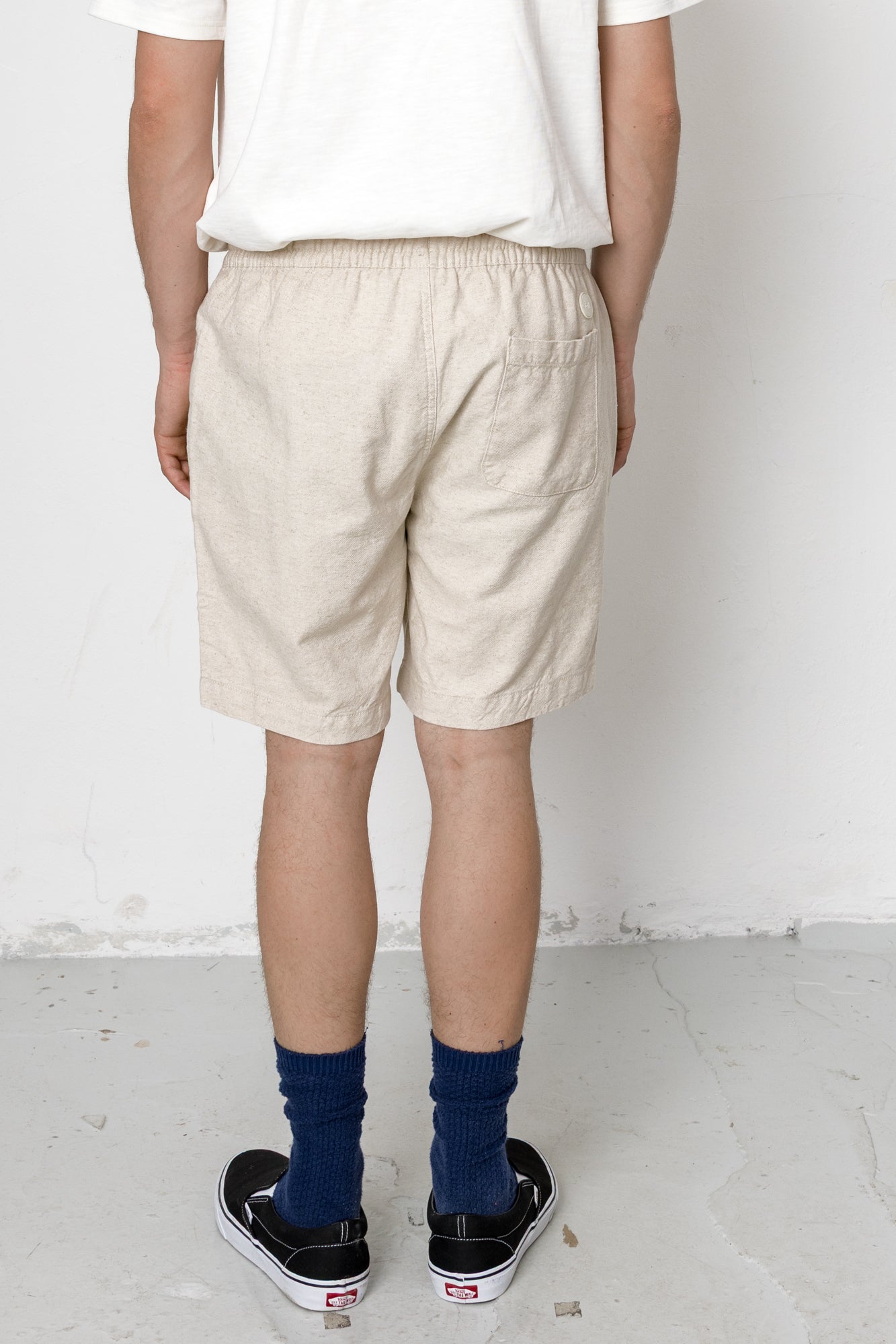 Person wearing beige shorts and navy socks on a white background