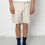 Person wearing beige shorts, white shirt, blue socks, and black shoes on a white background