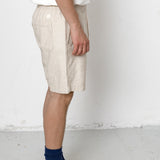 Person wearing beige shorts, black sneakers, and blue socks on a white background