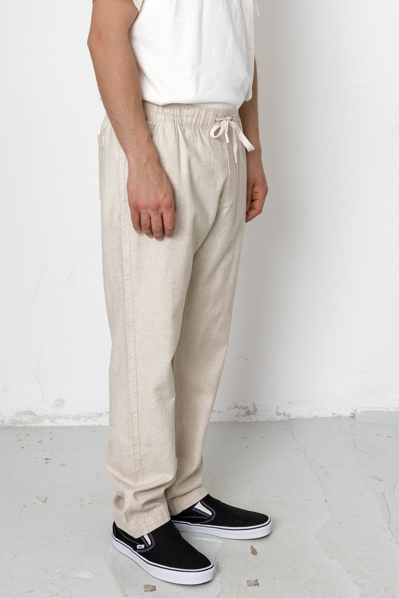 Person wearing beige pants and black shoes against a white background