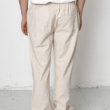 Person wearing beige pants and a white shirt against a plain background