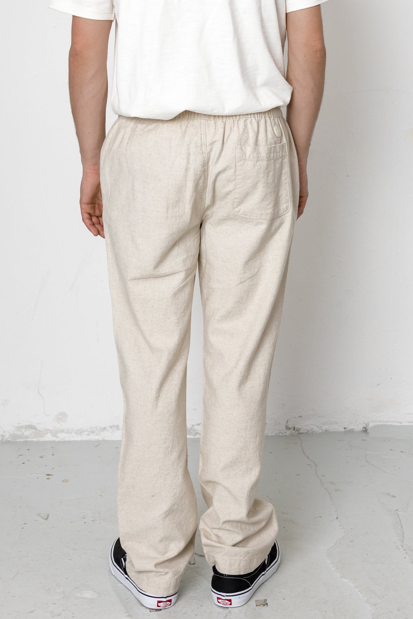 Person wearing beige pants and a white shirt against a plain background