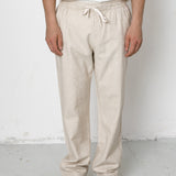 Person wearing beige sweatpants and black shoes on a white background
