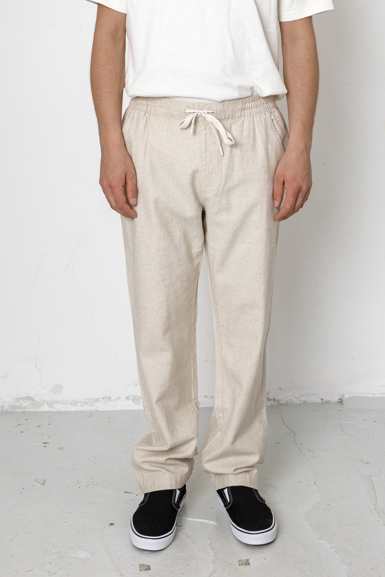 Person wearing beige sweatpants and black shoes on a white background
