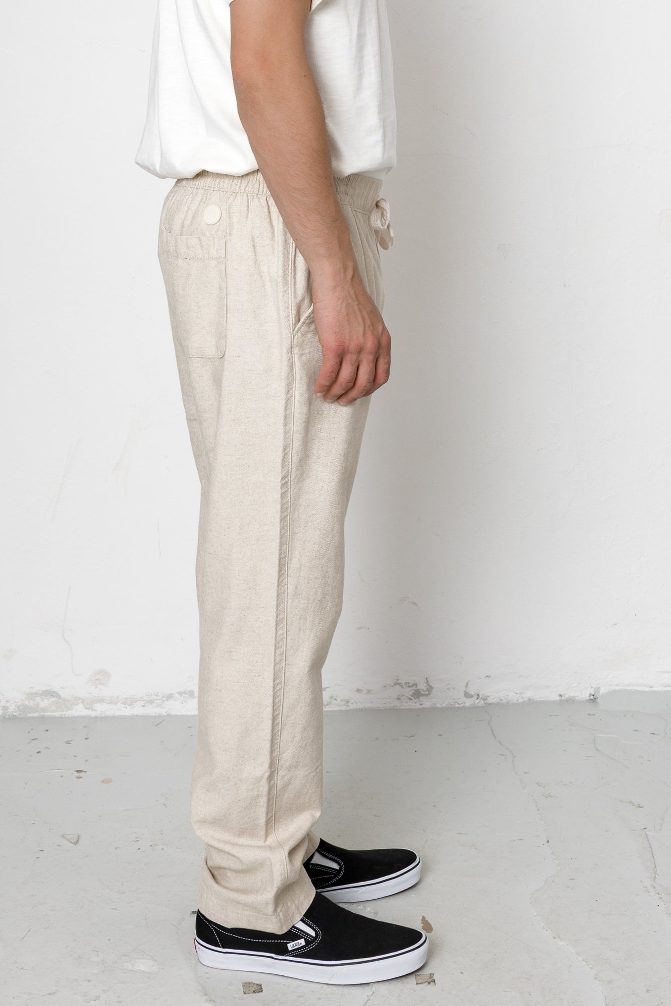 Person wearing beige pants and black shoes on a white background