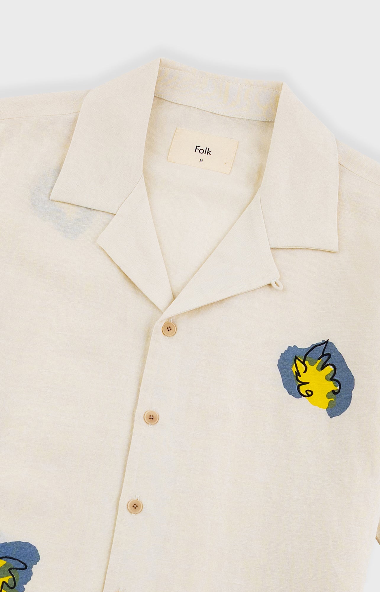 Beige shirt with colorful patches on a white background