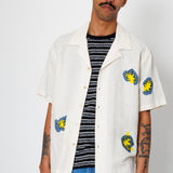 Man wearing a white shirt with colorful designs on a plain background
