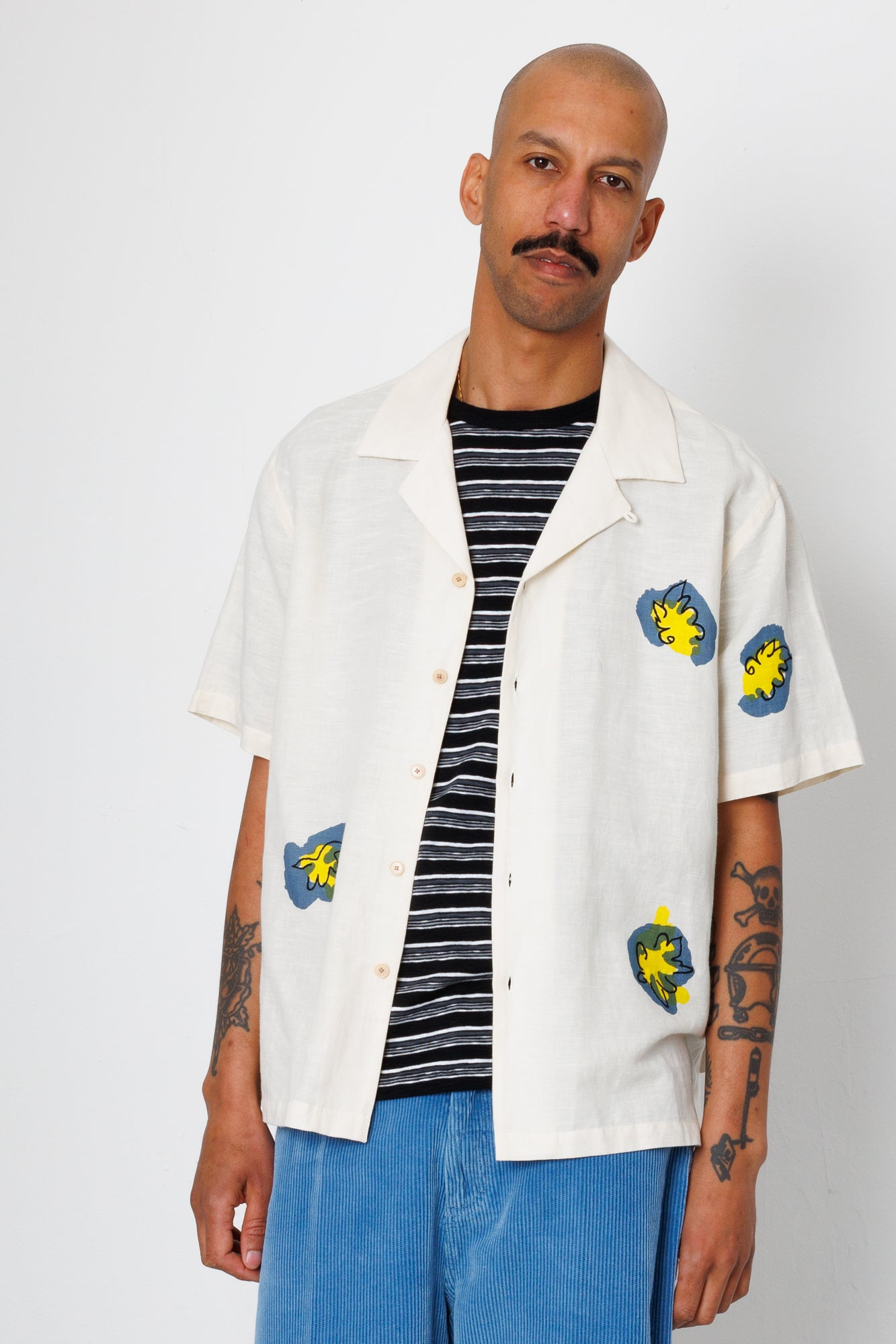 Man wearing a white shirt with colorful designs on a plain background