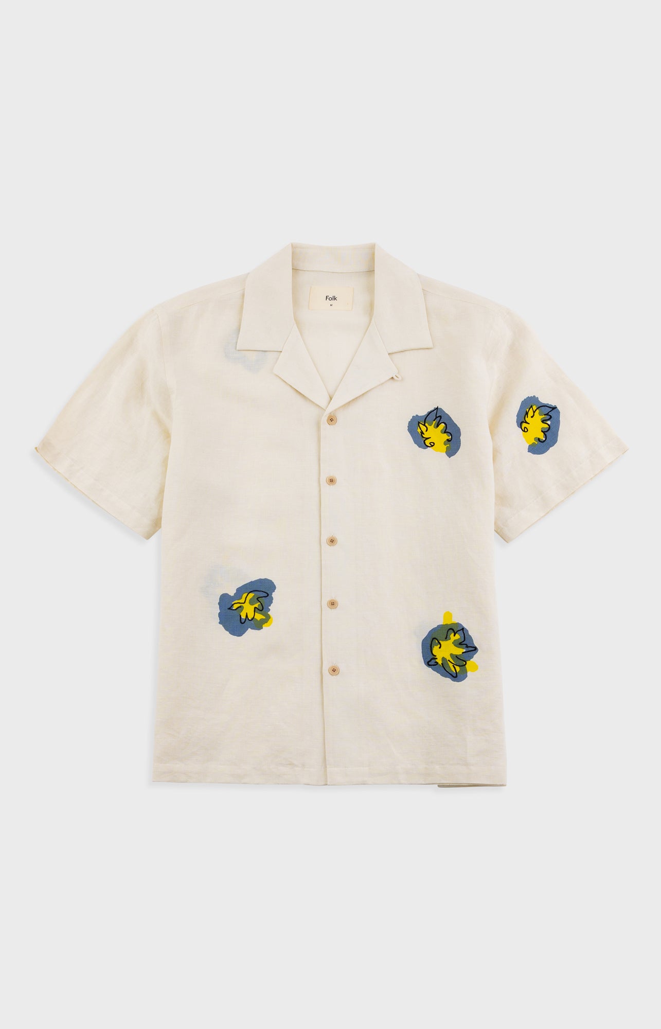 Beige shirt with embroidered designs on a white background