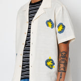 Person wearing a white jacket with colorful patches on a plain background