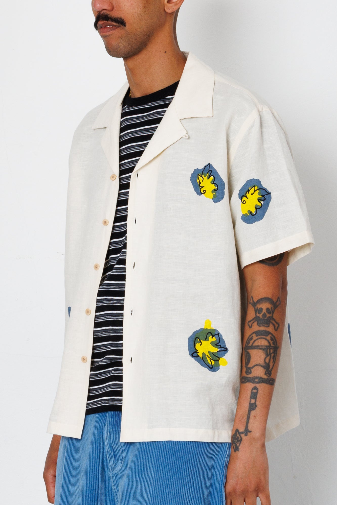 Person wearing a white jacket with colorful patches on a plain background