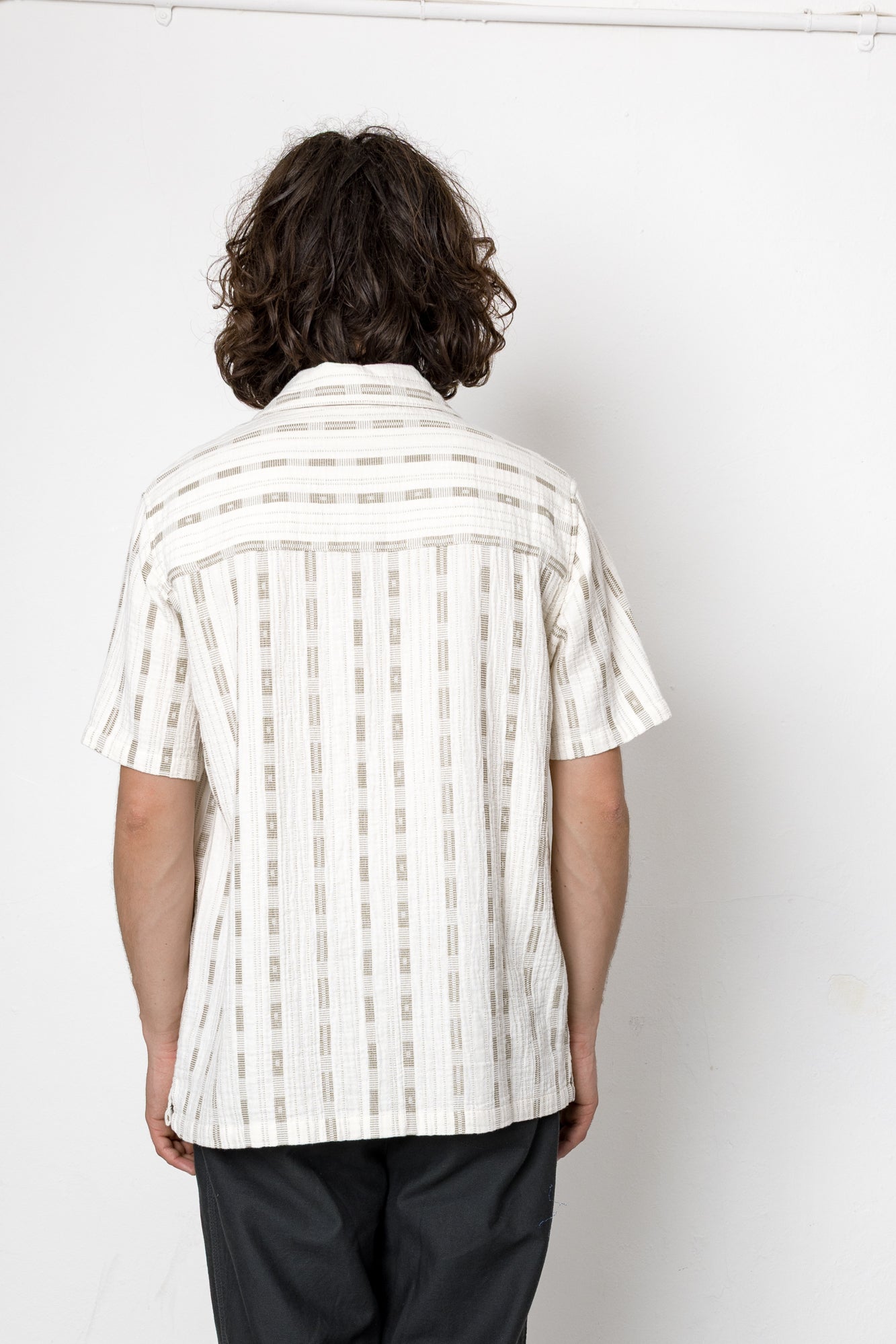 Person wearing a white striped shirt against a white background