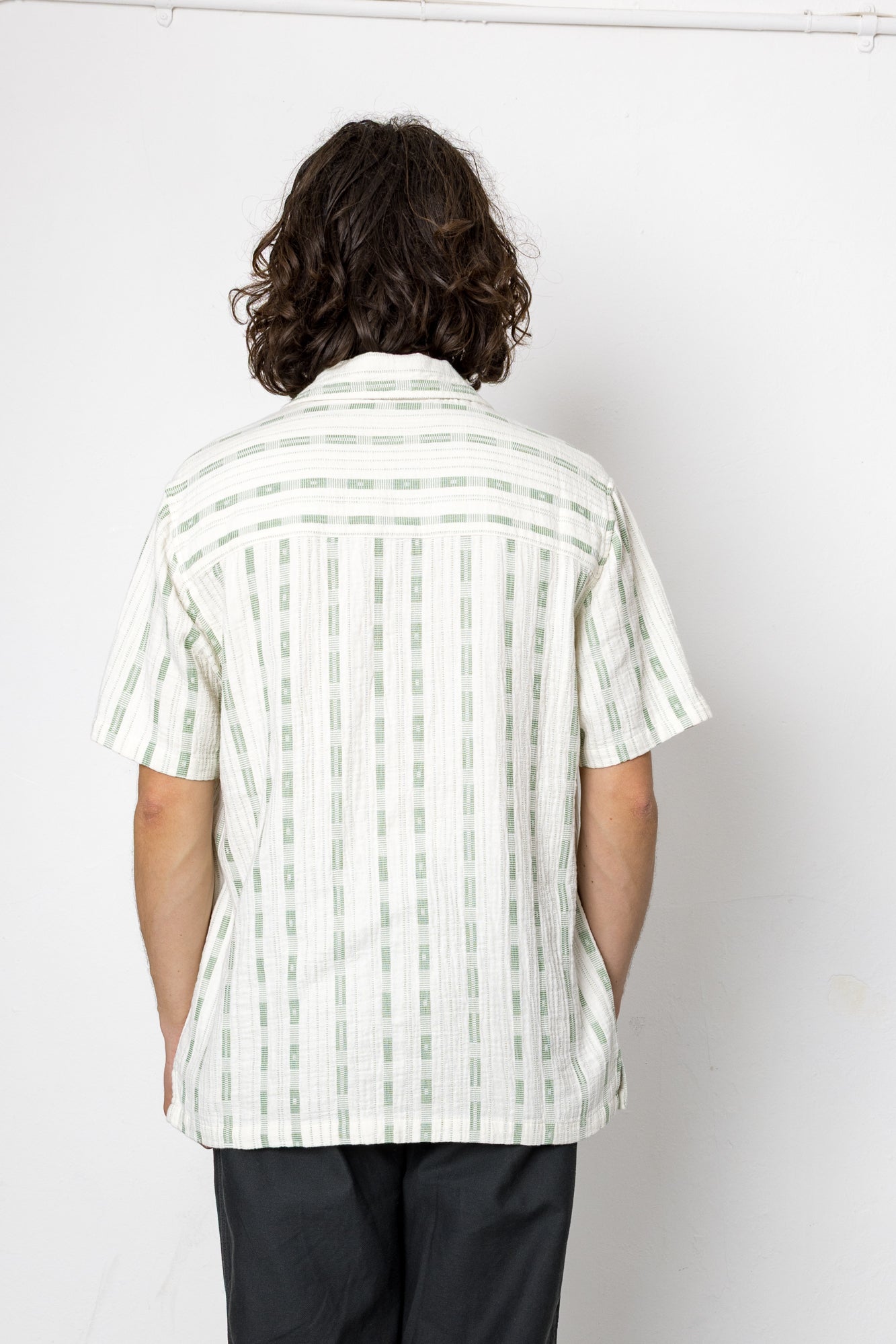 Person wearing a white and green striped shirt against a white background