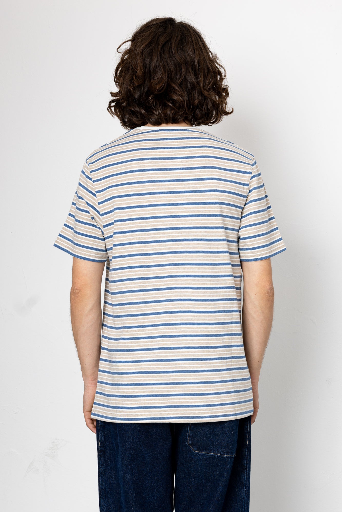 Person wearing a striped t-shirt and jeans on a plain background