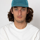 Man wearing a blue cap and white shirt against a plain background