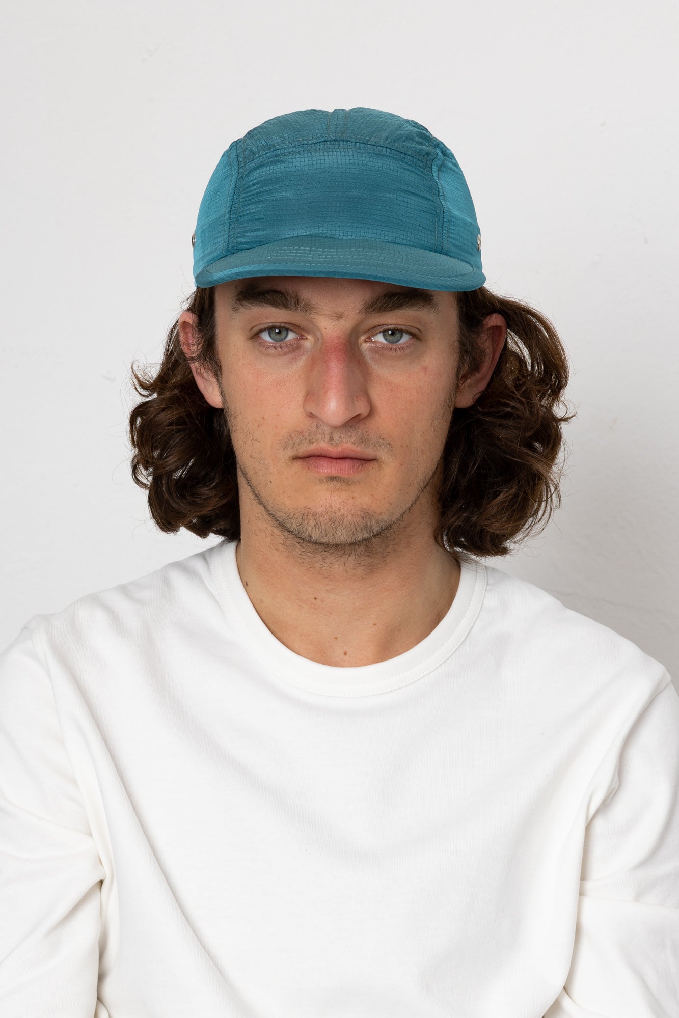 Man wearing a blue cap and white shirt against a plain background