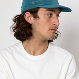 Man wearing a blue cap and white shirt against a plain background
