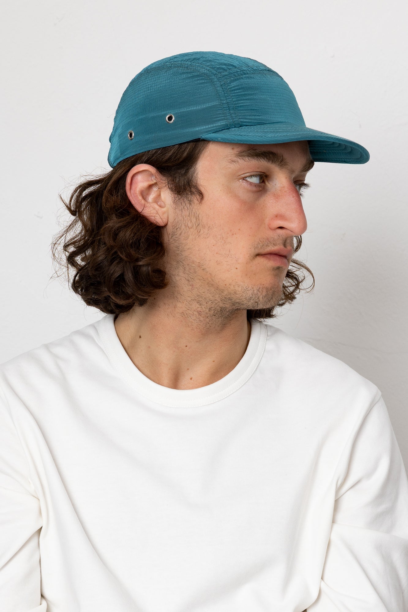 Man wearing a blue cap and white shirt against a plain background