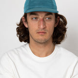 Man wearing a blue cap and white shirt against a plain background
