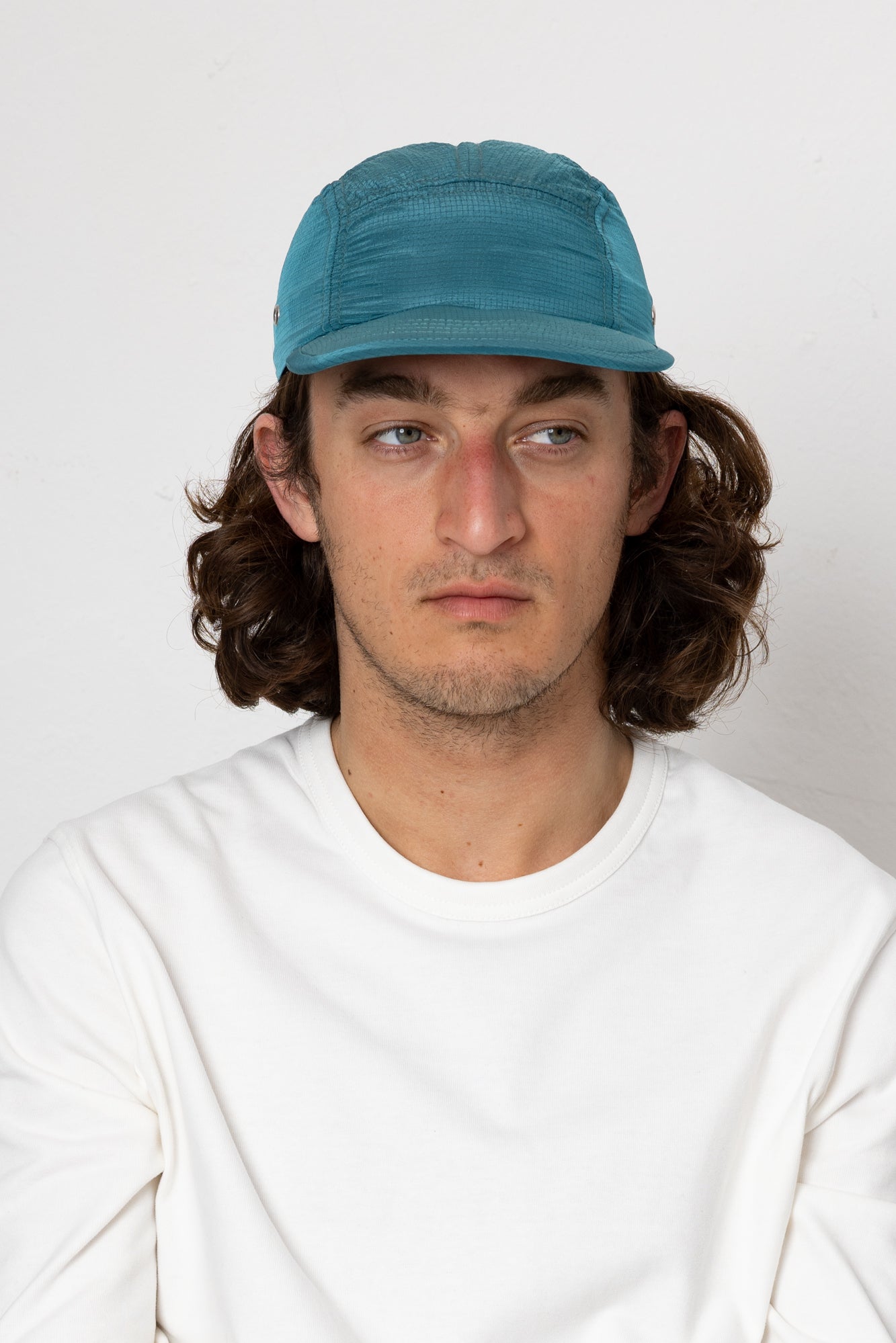 Man wearing a blue cap and white shirt against a plain background