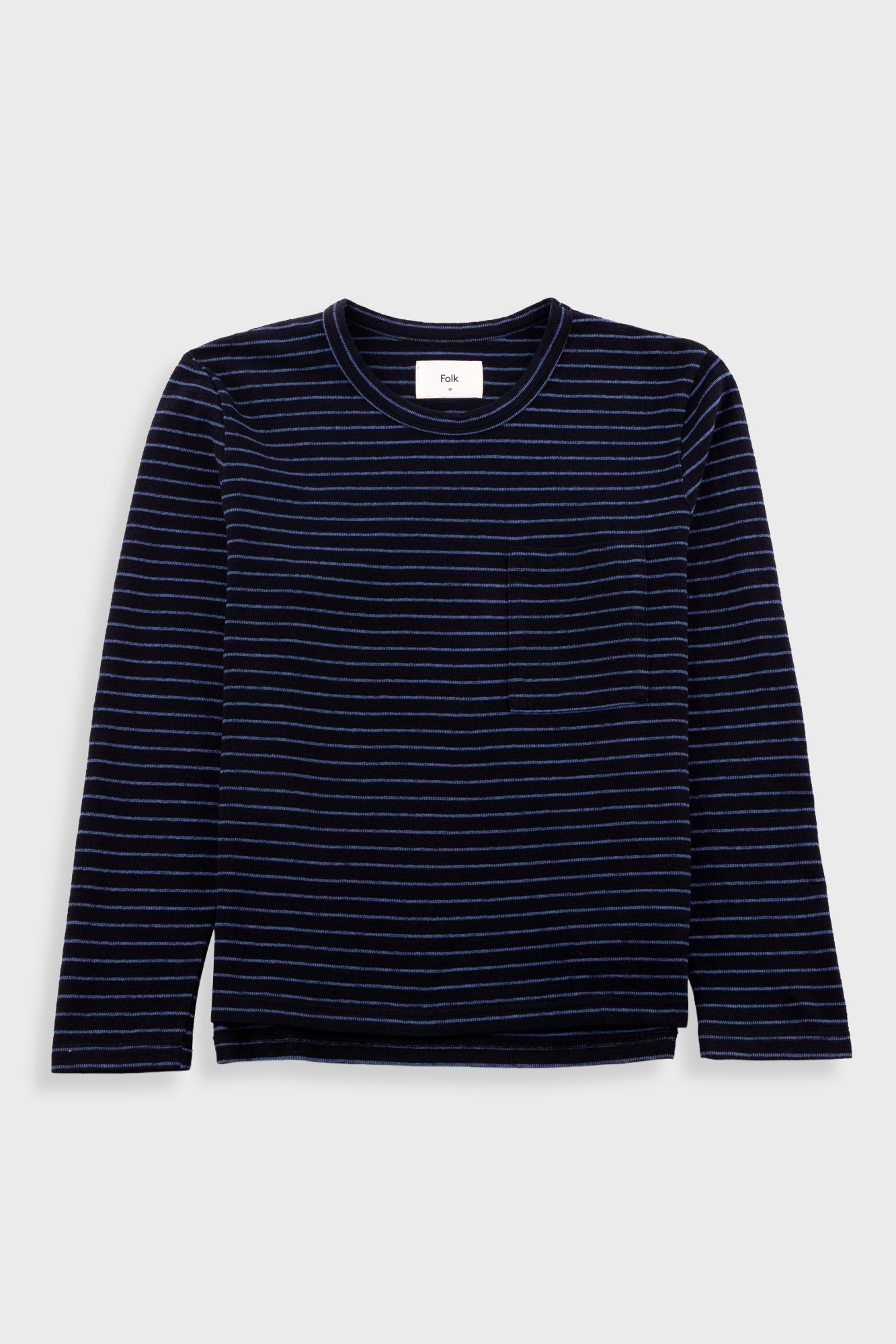 A navy blue long-sleeve crewneck shirt with thin horizontal white stripes and a single chest pocket, displayed flat against a light gray background.