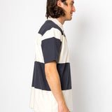 Man wearing a navy and white striped polo shirt against a white background