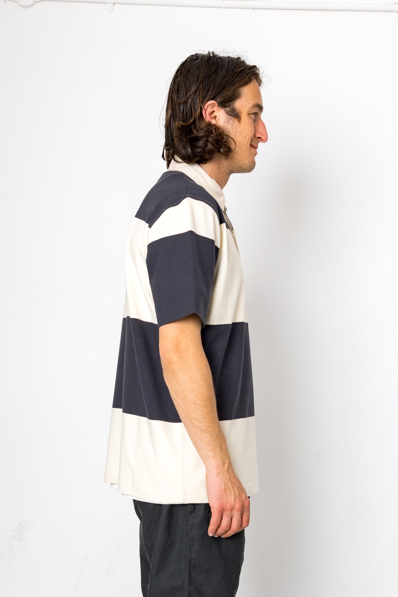 Man wearing a navy and white striped polo shirt against a white background