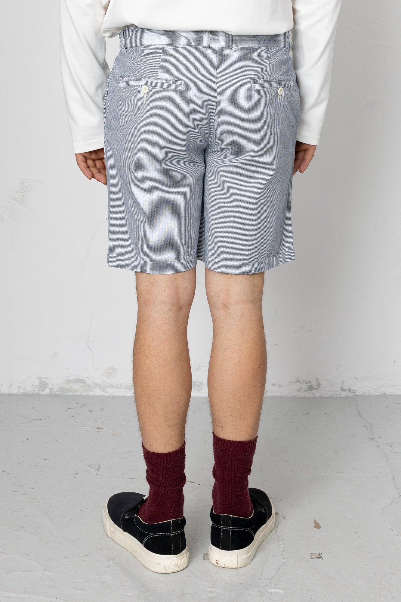 Person wearing light blue shorts and maroon socks on a plain background